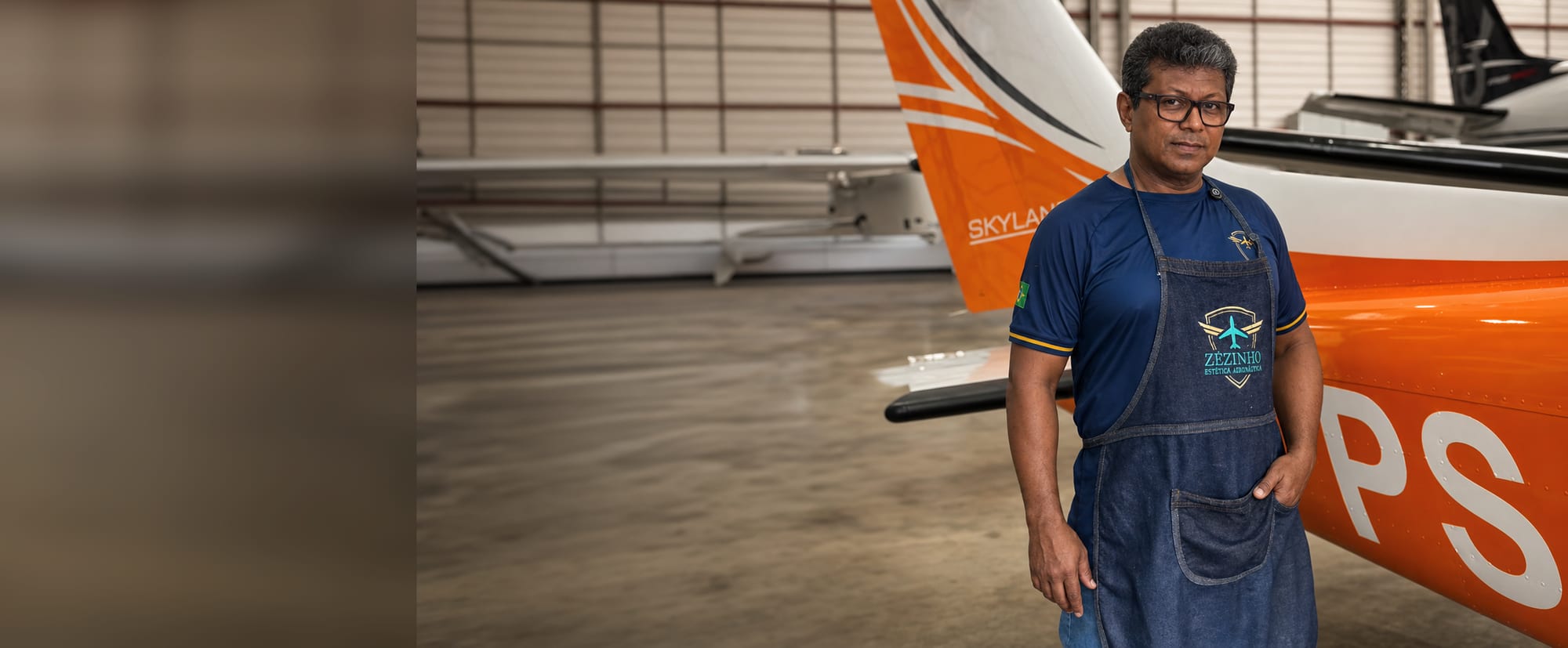 Zezinho at the hangar, wearing his apron, next to a Cessna Skylane